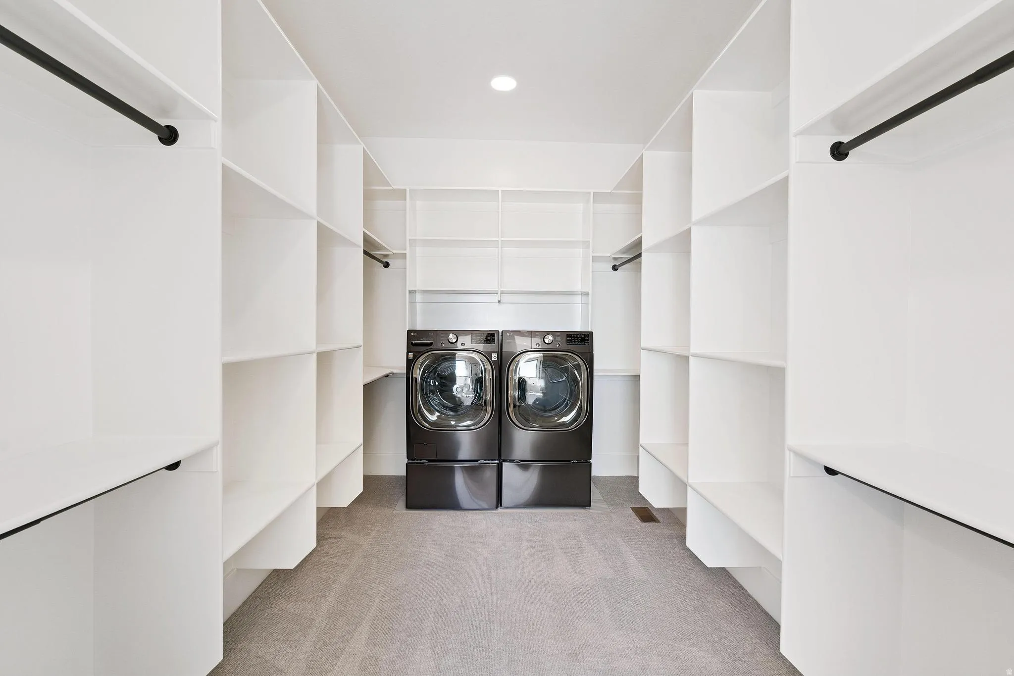 Laundry room featuring light colored carpet and washing machine and clothes dryer