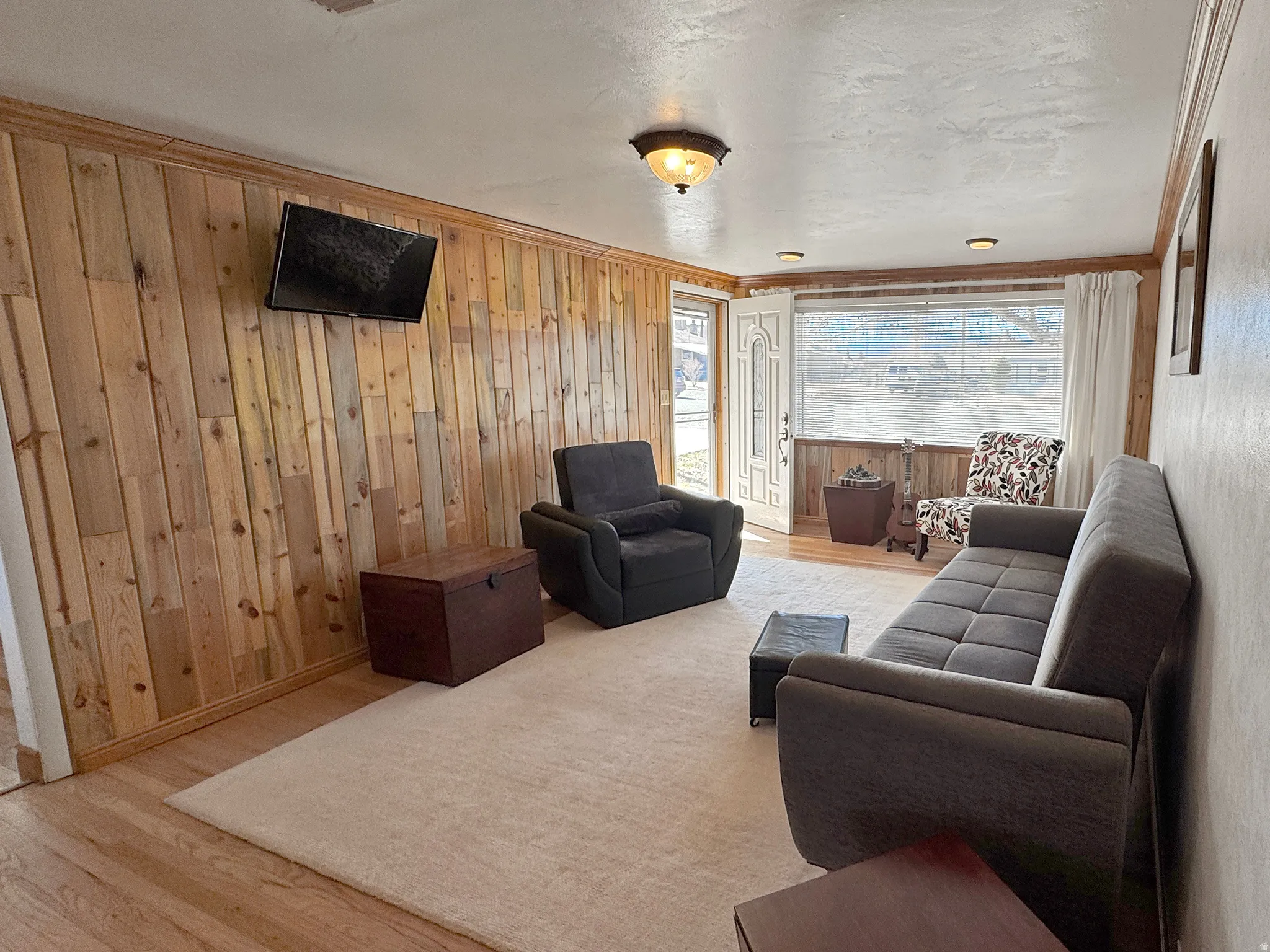 Living room featuring wood finished floors, wood walls, and crown molding