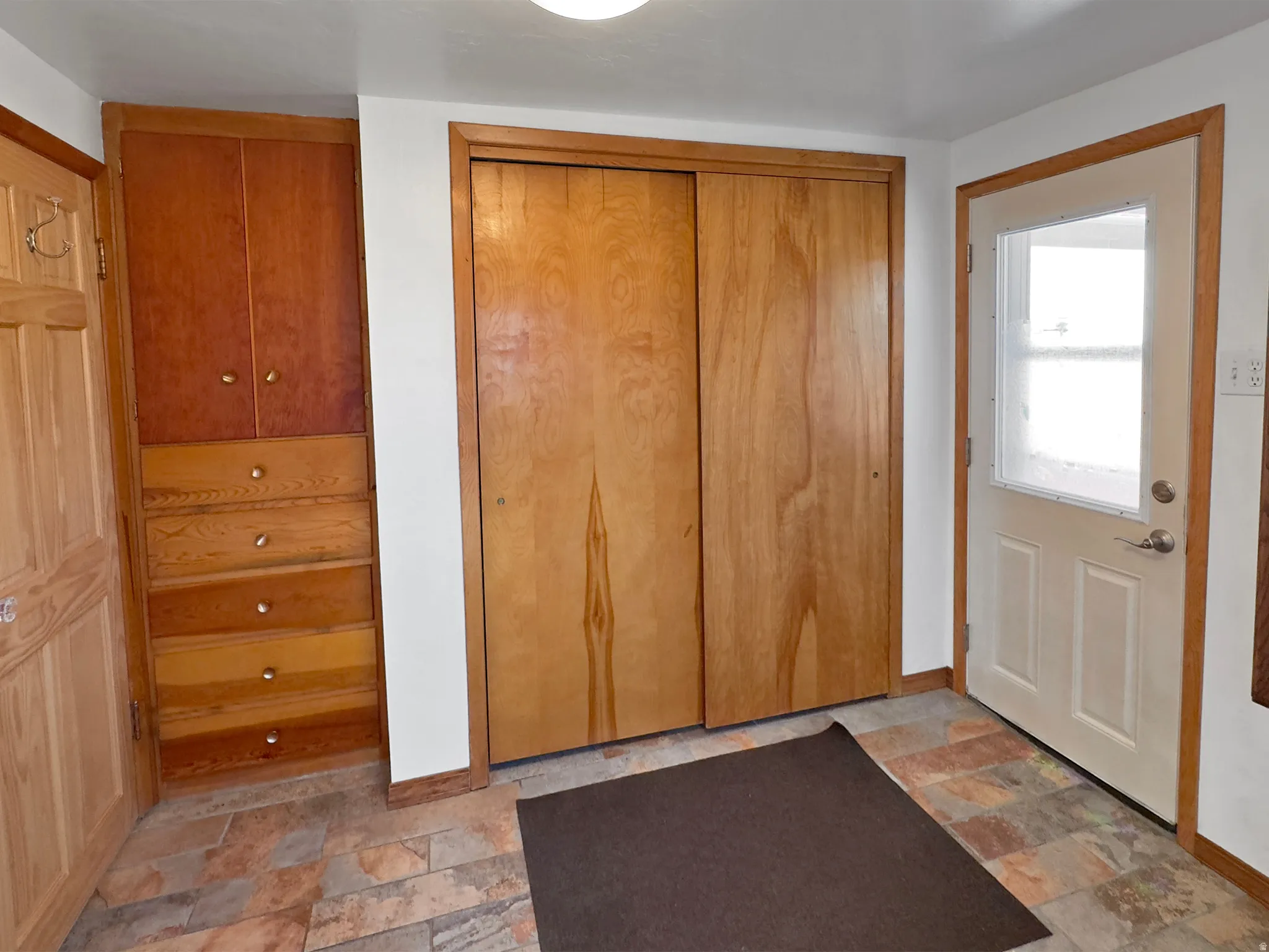 Entryway featuring stone finish floors and baseboards