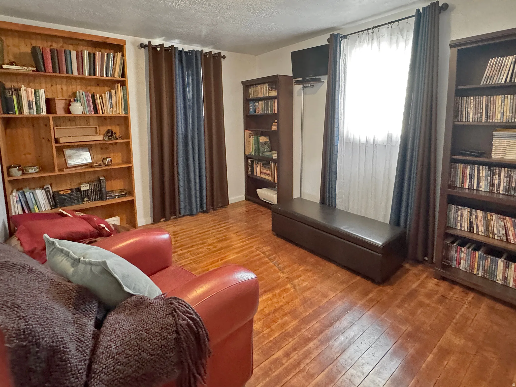 Living area featuring hardwood / wood-style floors, a textured ceiling, and built in shelves