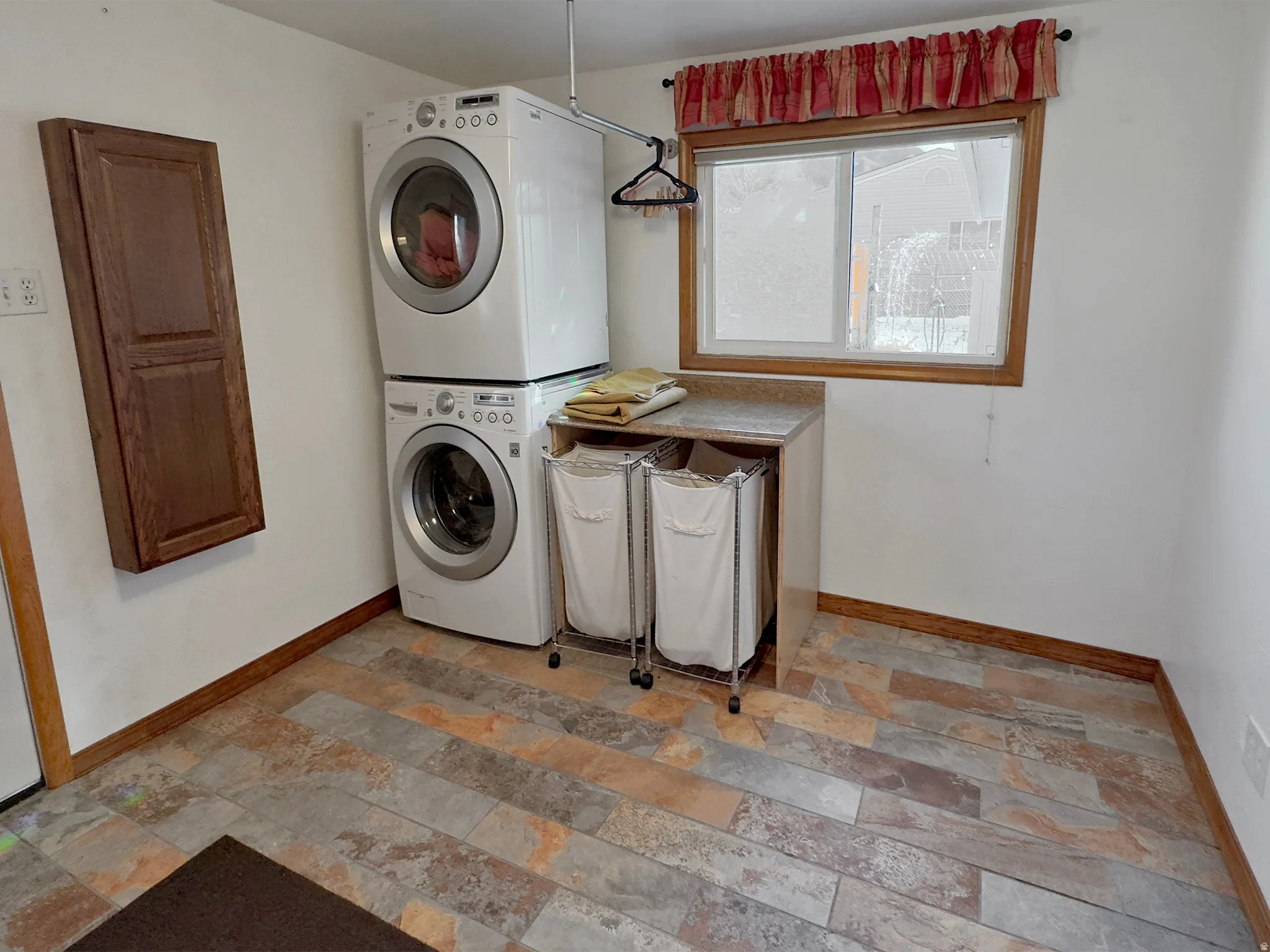 Laundry room featuring light stone finish floors and stacked washer / drying machine