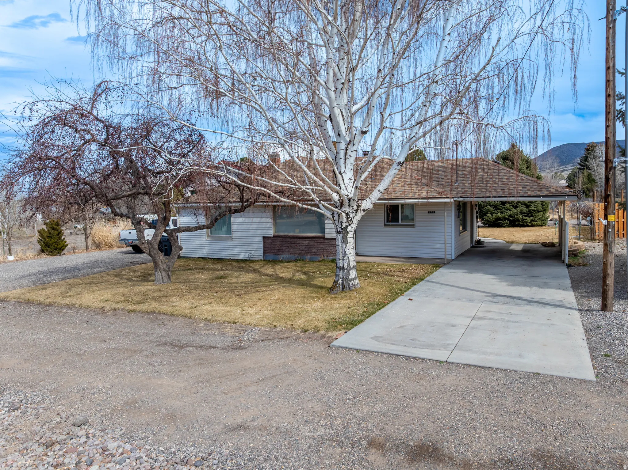 View of front of property with driveway, a carport, a front yard, a mountain view, and a chimney