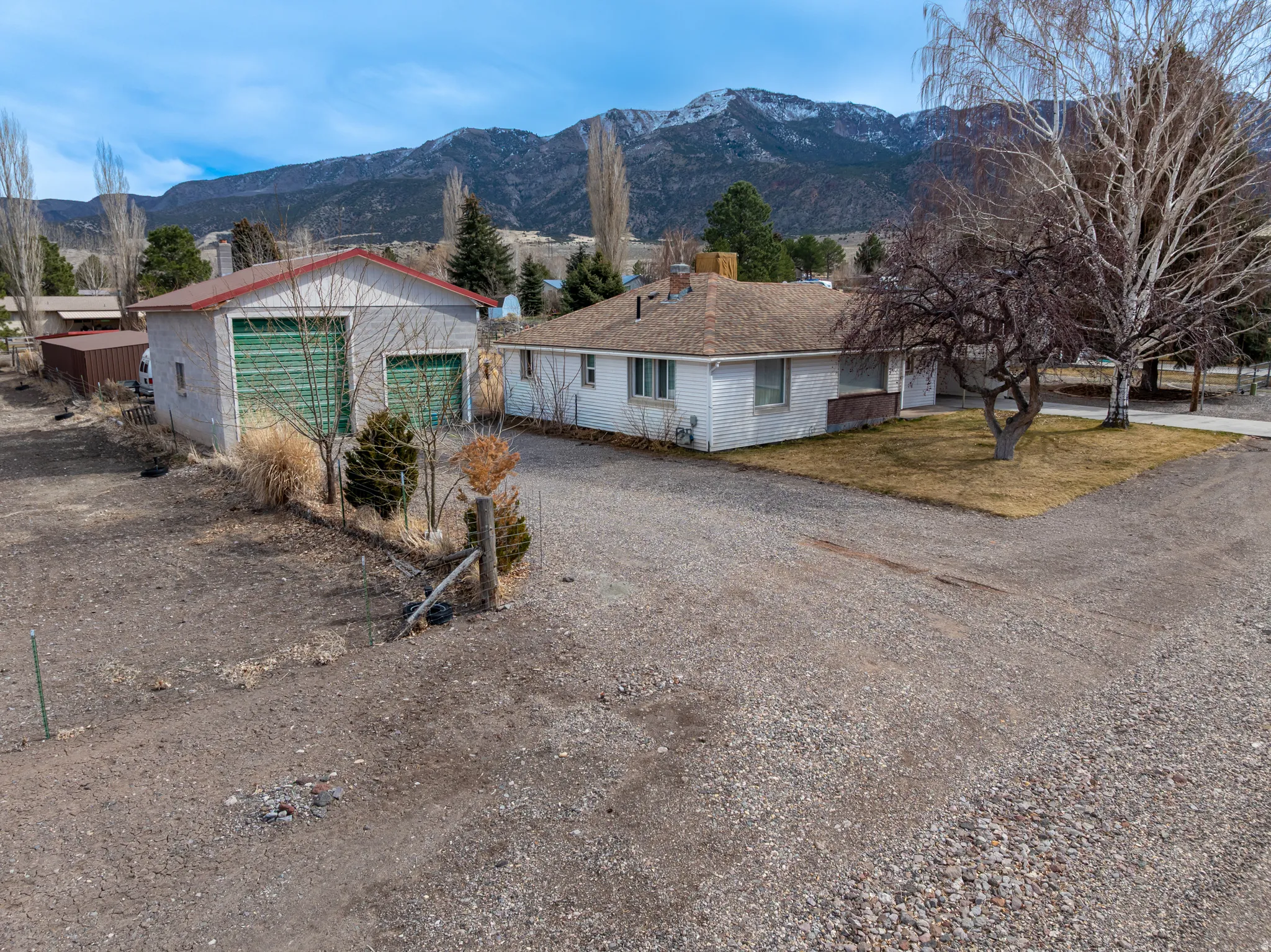 View of front of home featuring driveway, an outbuilding, a mountain view, and a chimney