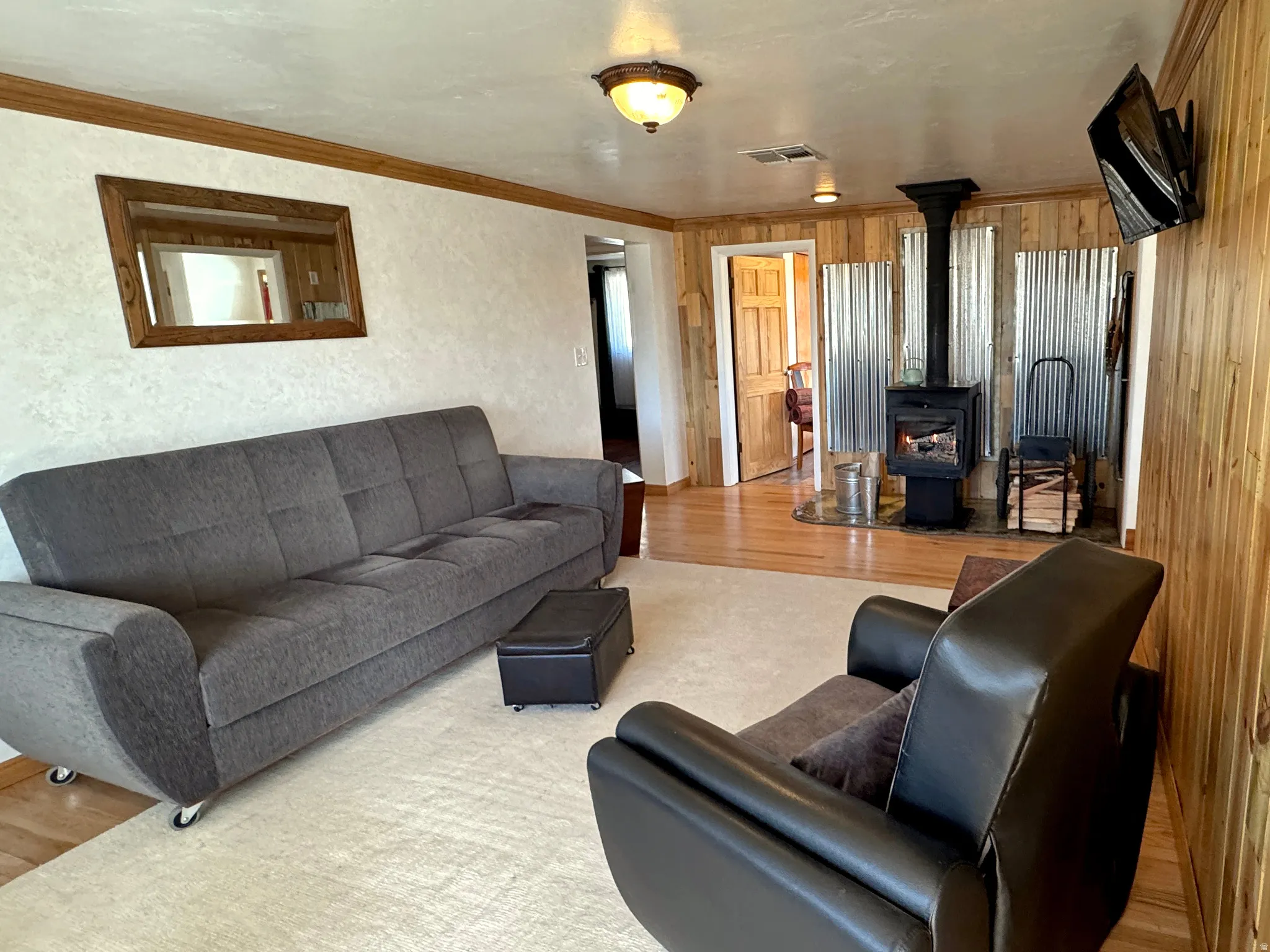 Living area with wood finished floors, crown molding, and a wood stove