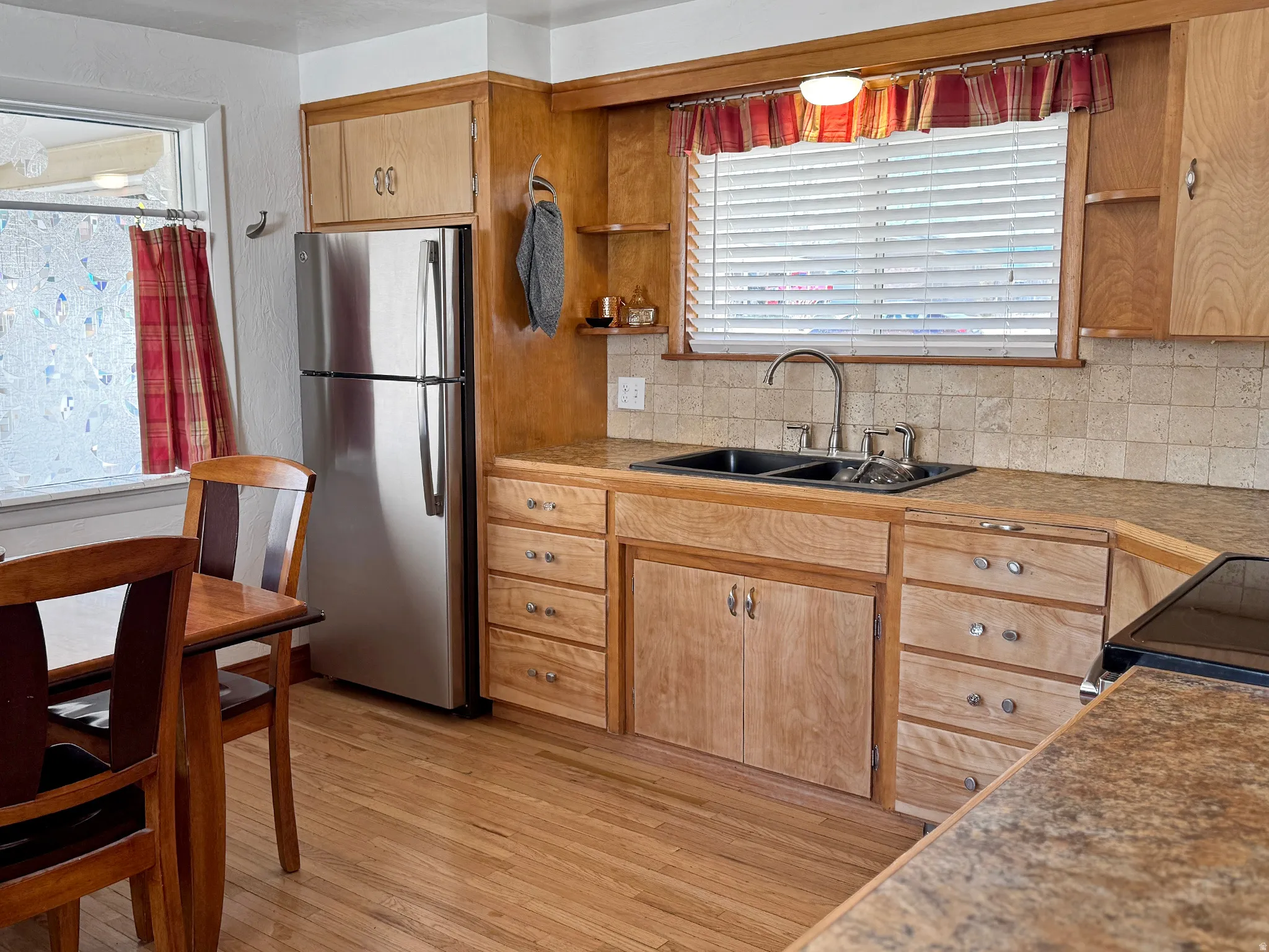 Kitchen with freestanding refrigerator, light wood-style flooring, tasteful backsplash, black range with electric stovetop, and open shelves
