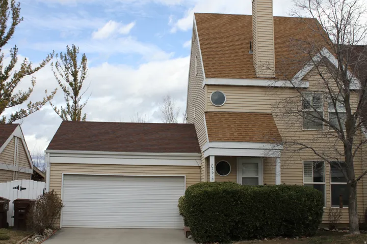 View of front of home with roof with shingles, concrete driveway, a garage, and a chimney