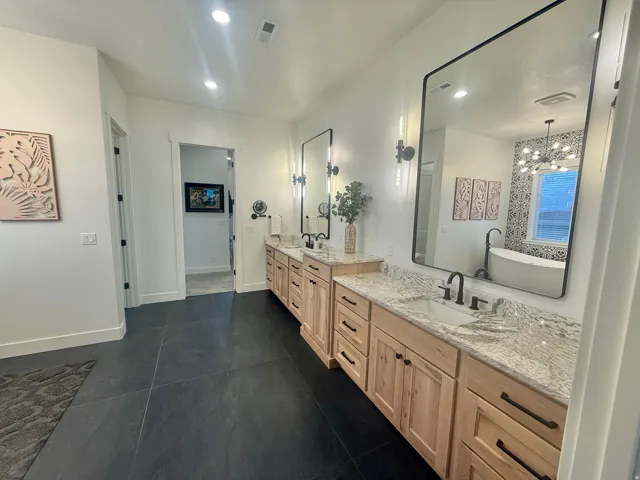 Bathroom featuring double vanity, hanging lights, and a freestanding bath