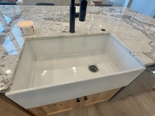Kitchen view of a sink and light stone counters