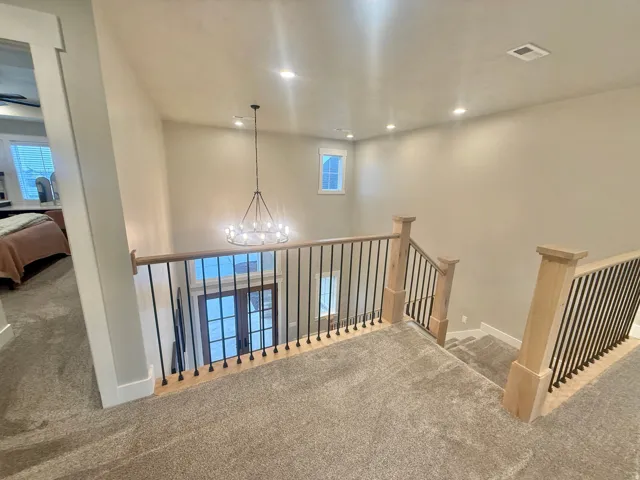 Hall featuring carpet floors, a chandelier, and an upstairs landing