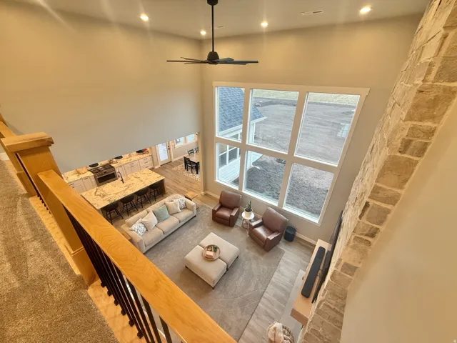 Living area with a high ceiling, ceiling fan, wood finished floors, and recessed lighting