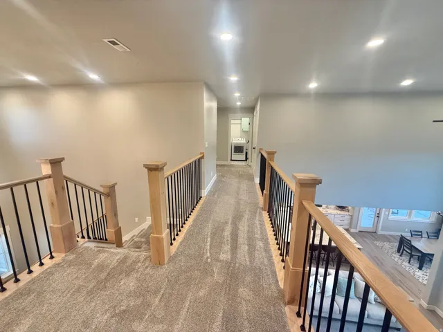 Hall with light carpet, an upstairs landing, and recessed lighting