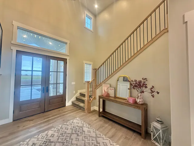 Foyer entrance with french doors, light wood-type flooring, and a high ceiling