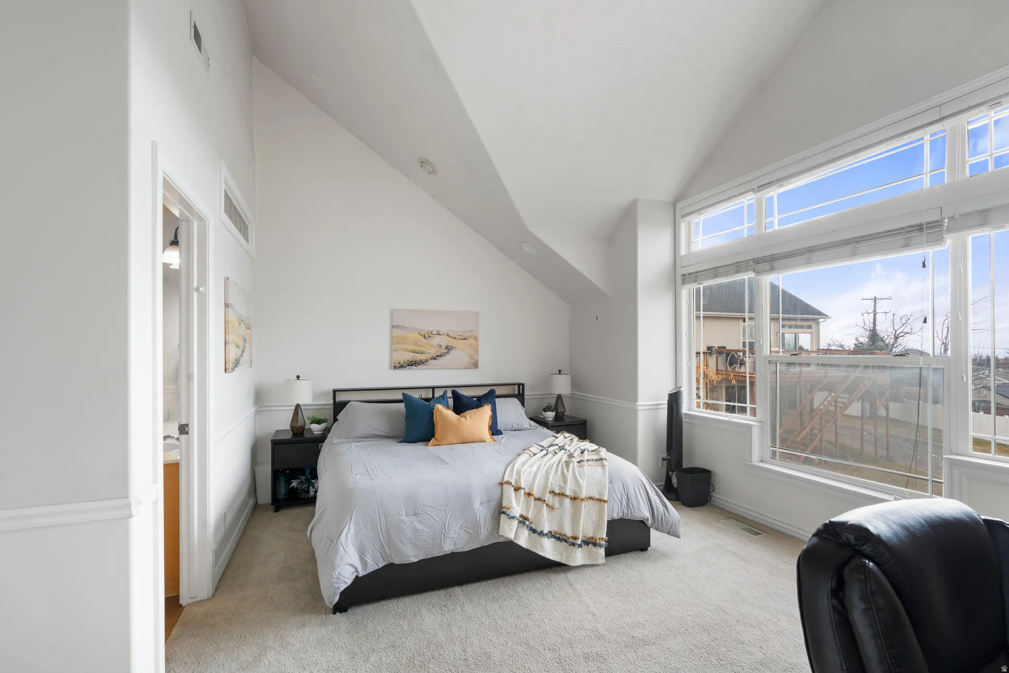 Primary Bedroom with light colored carpet and vaulted ceiling