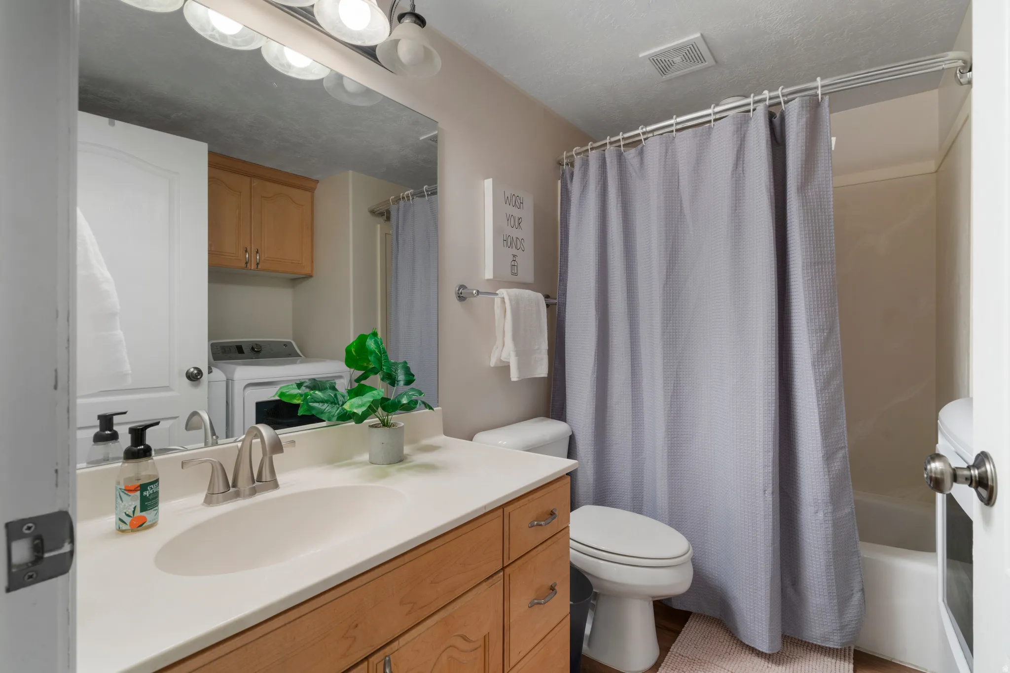 Bathroom with vanity, washer / clothes dryer, and shower / bath combo