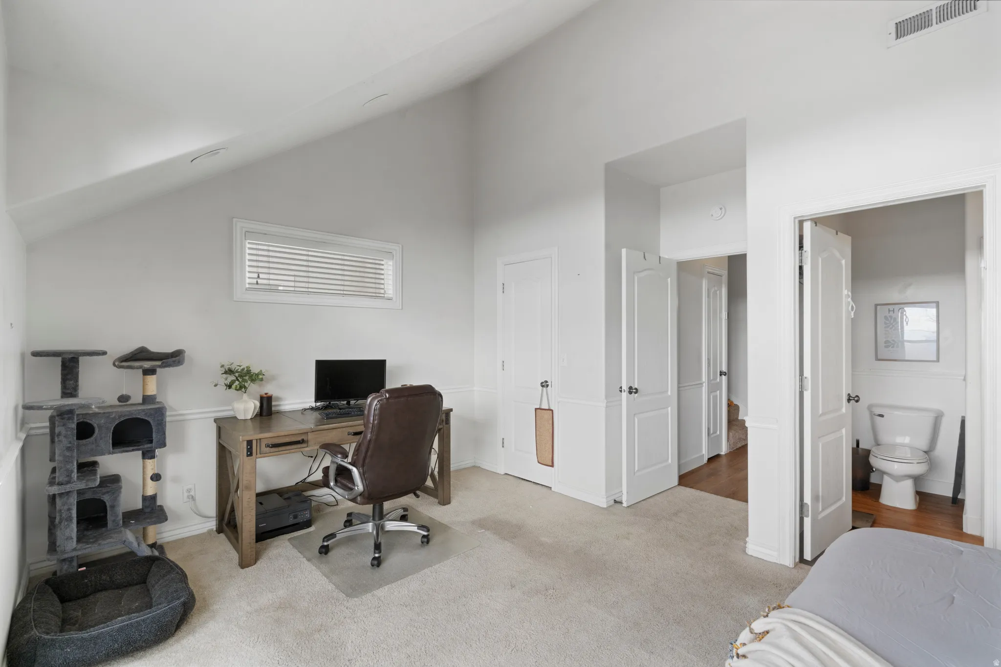 Primary Bedroom featuring light colored carpet and lofted ceiling