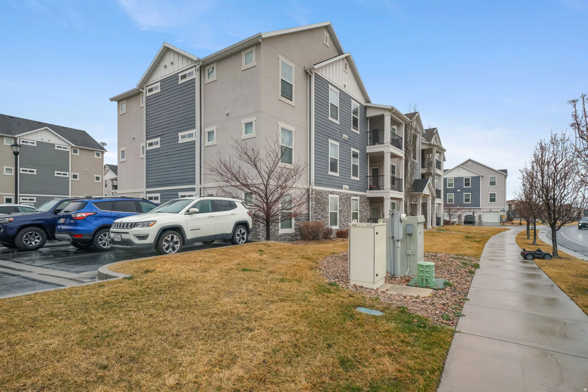 Exterior space with board and batten siding, a lawn, and uncovered parking