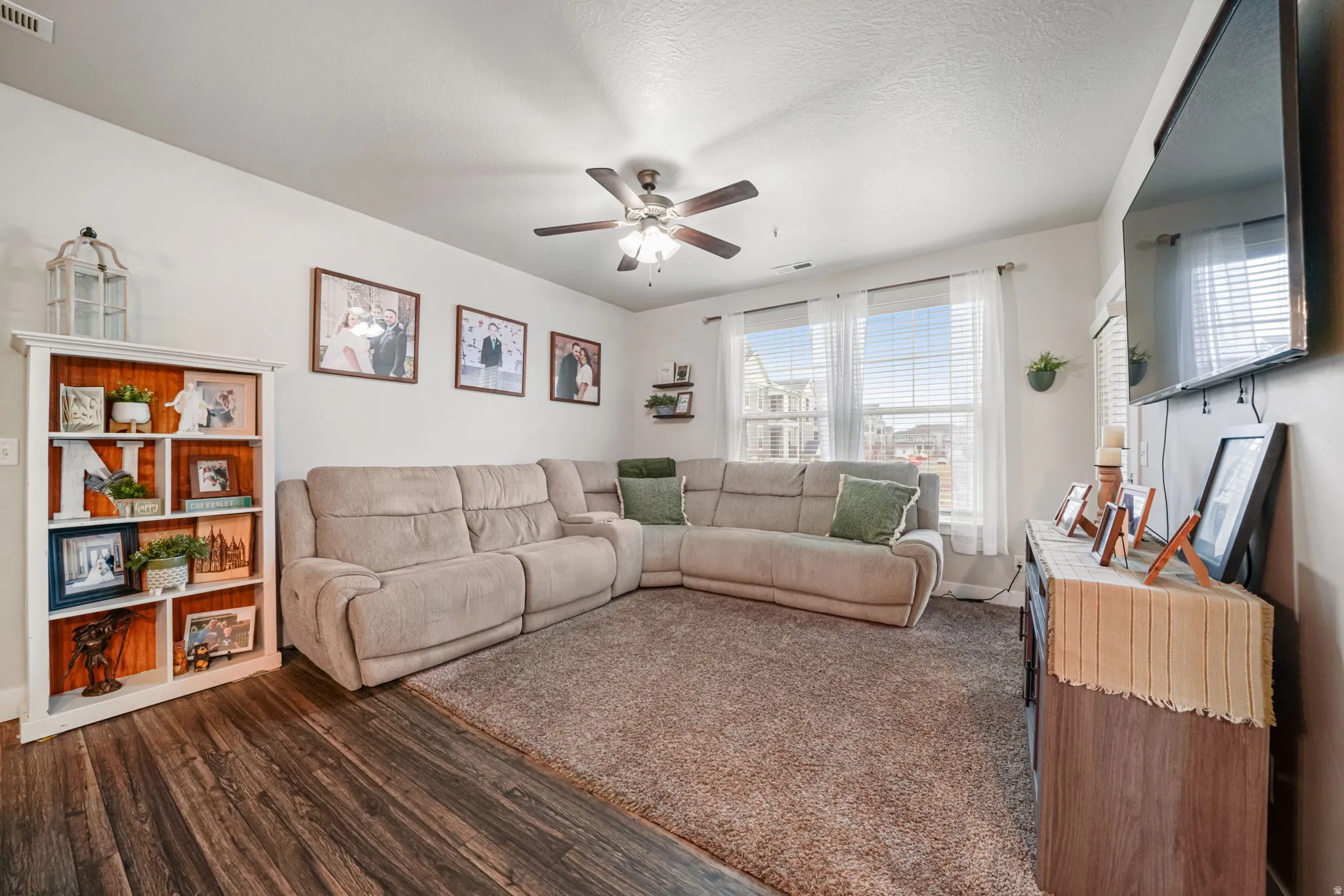Living room featuring dark wood finished floors, a ceiling fan, and a textured ceiling