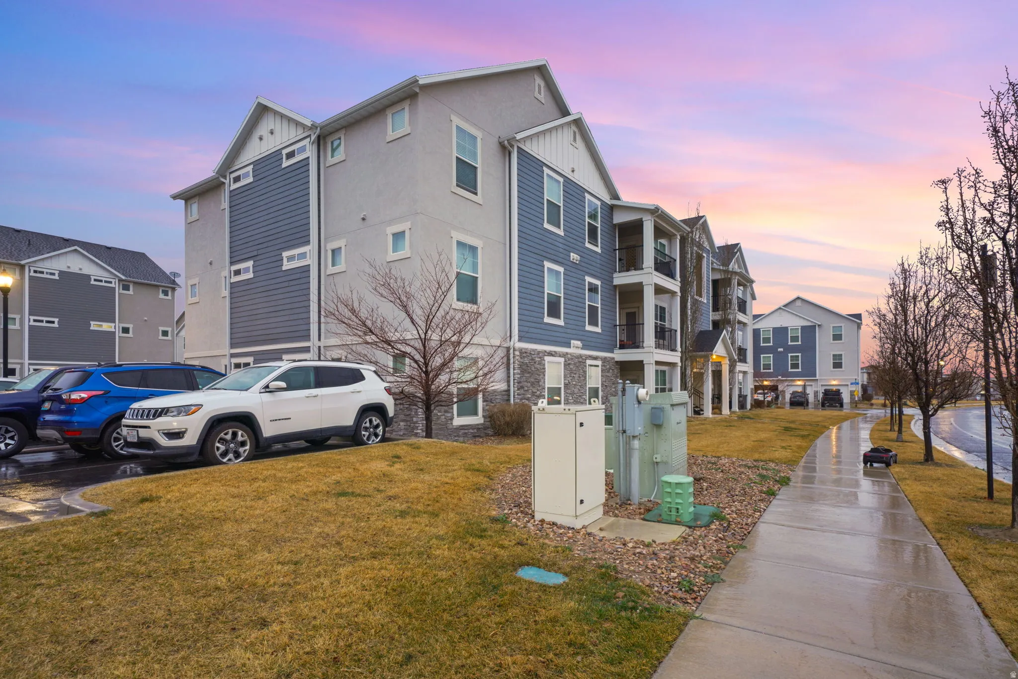 Property exterior at dusk featuring board and batten siding, a yard, stone siding, and a residential view