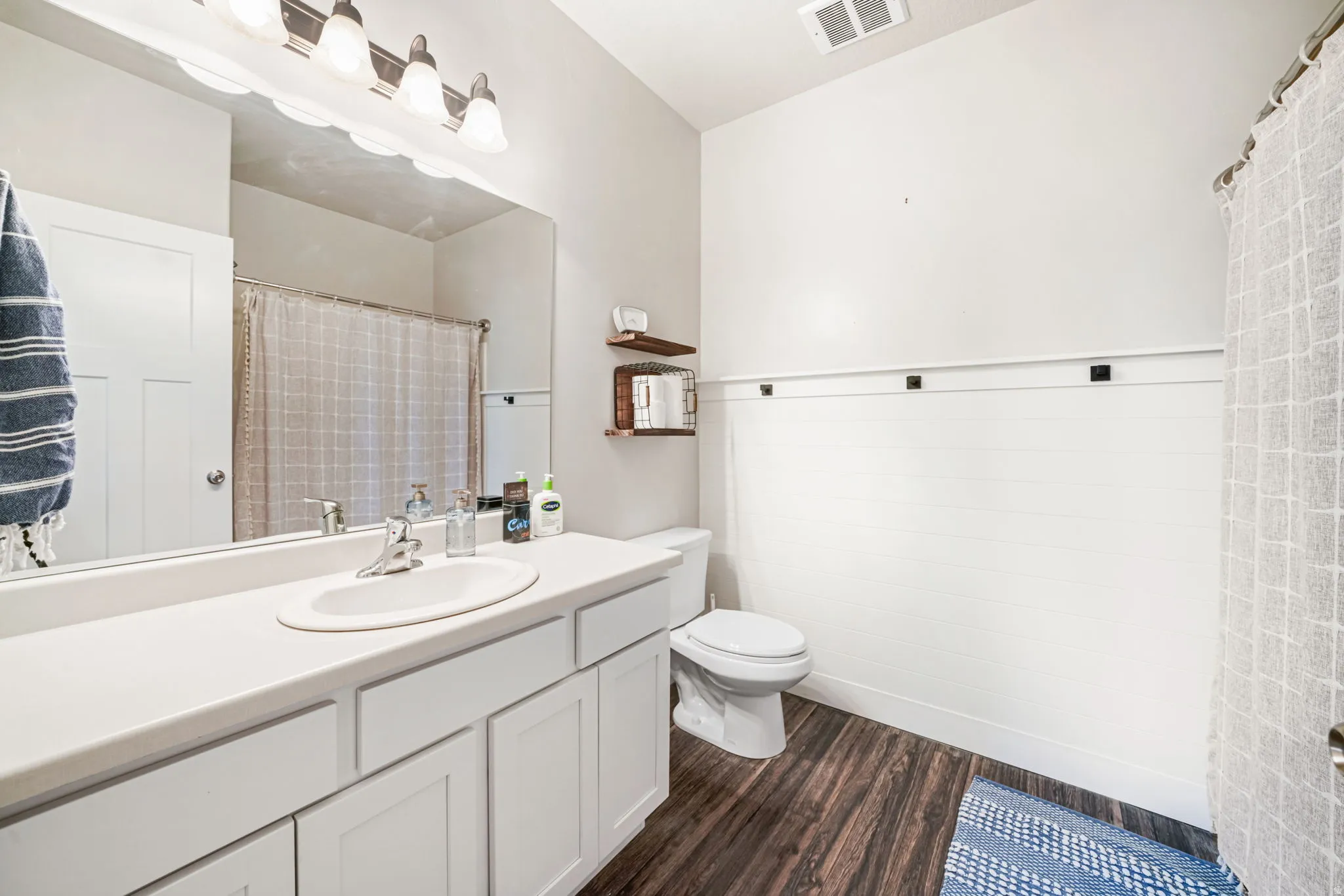 Full bathroom featuring vanity, dark wood-style floors, and curtained shower