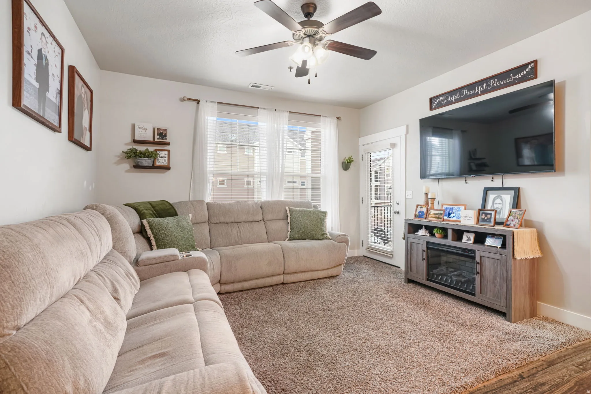 Carpeted living area featuring ceiling fan and baseboards