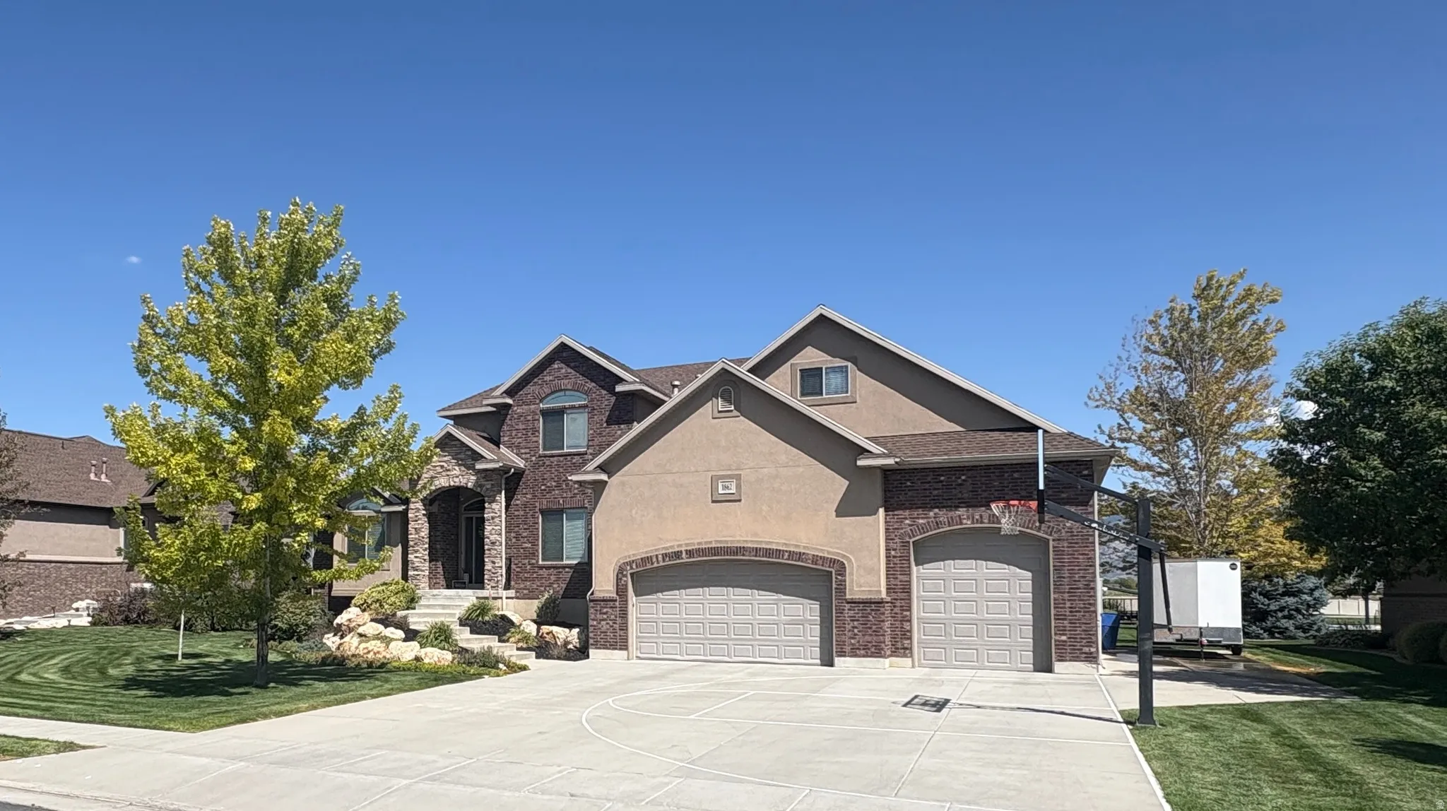 View of front of home with concrete driveway, stucco siding, brick siding, and a front yard