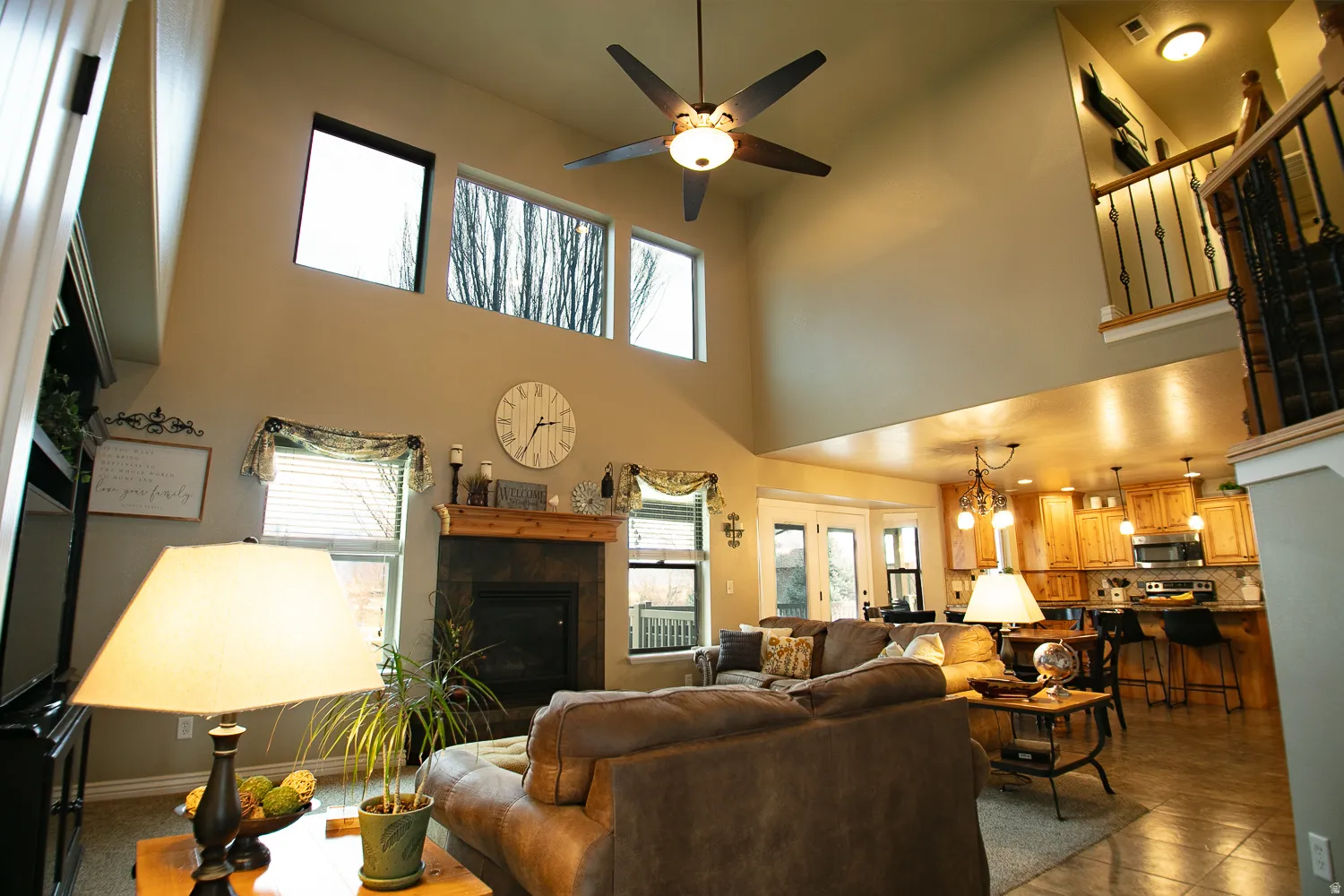 Living room featuring a ceiling fan, a tiled fireplace, and a high ceiling
