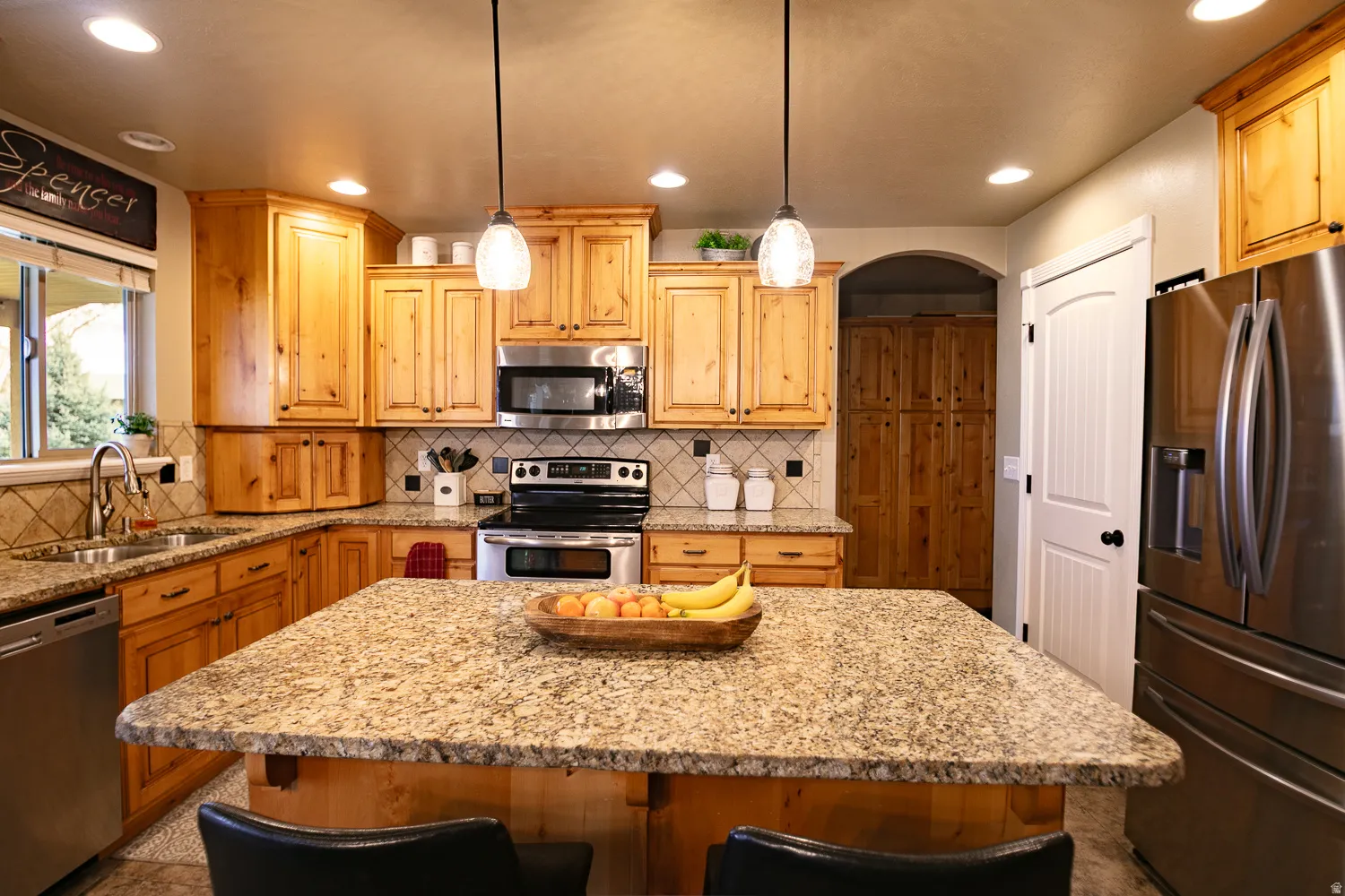 Kitchen featuring stainless steel appliances, light stone counters, a kitchen island, a breakfast bar, and pendant lighting