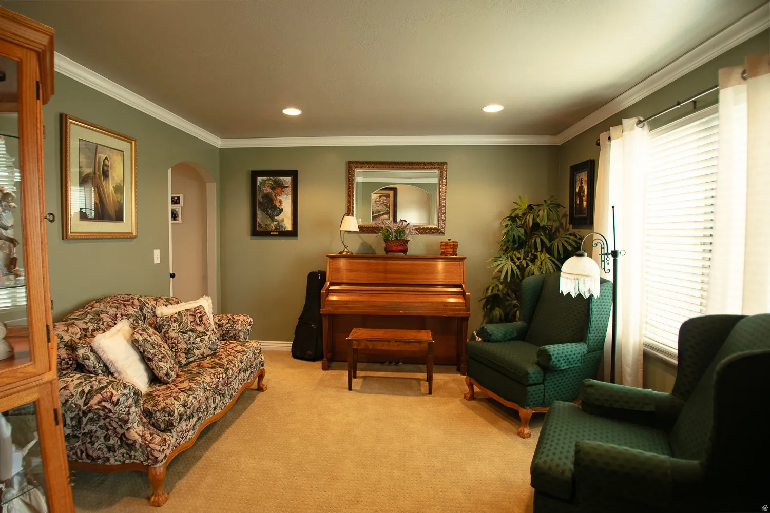 Living area featuring arched walkways, crown molding, carpet floors, and recessed lighting