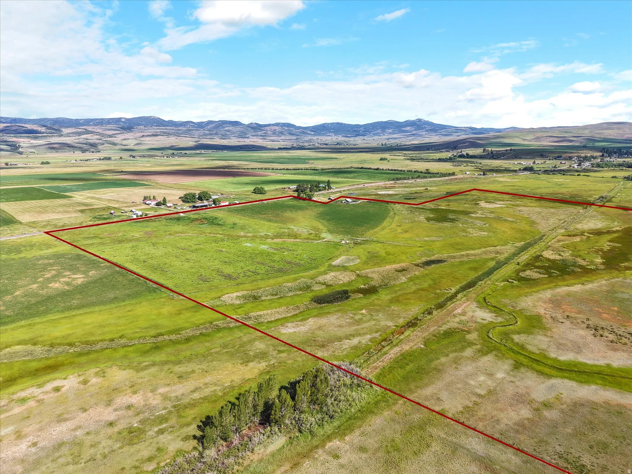 Expansive land parcel featuring open fields, distant mountain backdrop, and a winding waterway