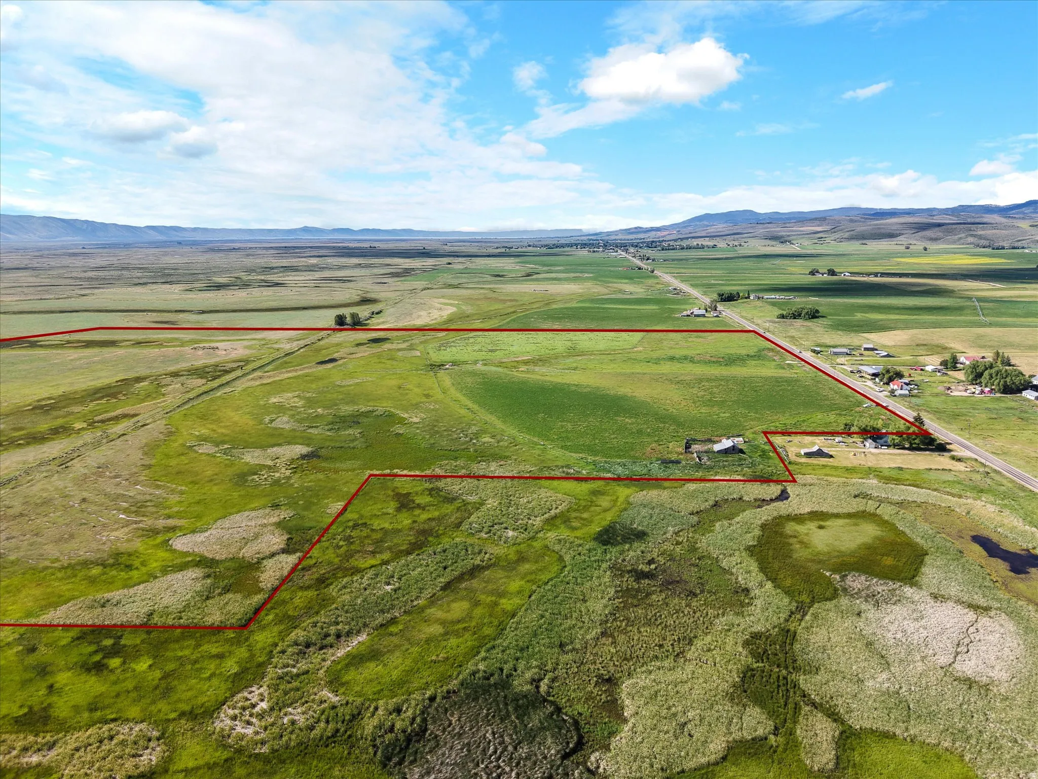 Expansive rural landscape featuring a mix of green fields and wetland areas