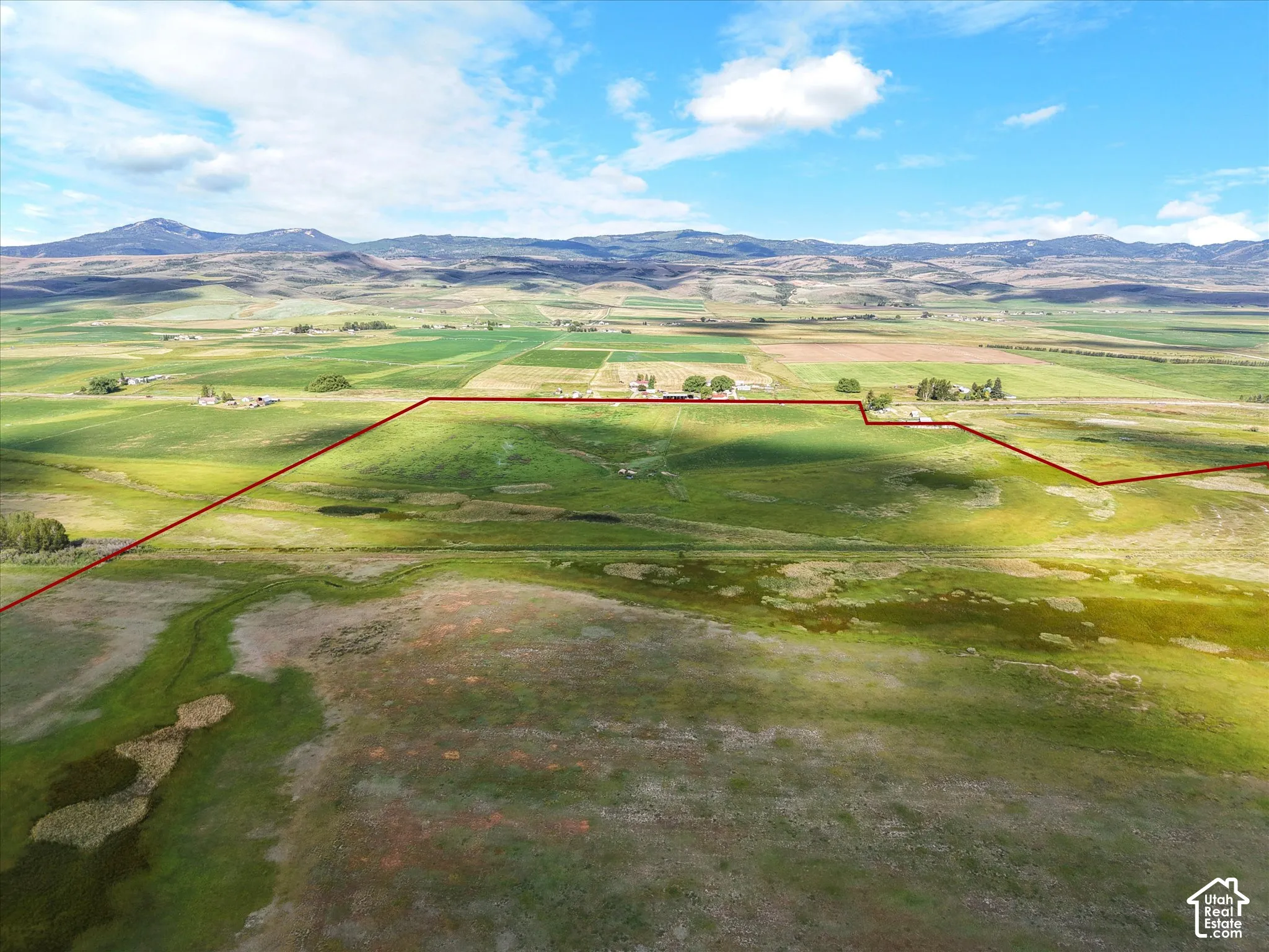 Expansive agricultural land featuring a diverse landscape of fields, bordered by distant mountains