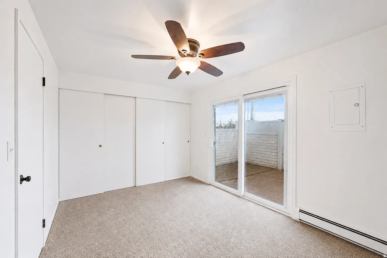 Carpeted room with white walls and a ceiling fan