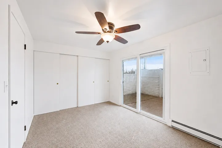 Carpeted room with white walls and a ceiling fan