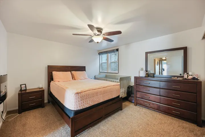 Bedroom with light carpet and a ceiling fan