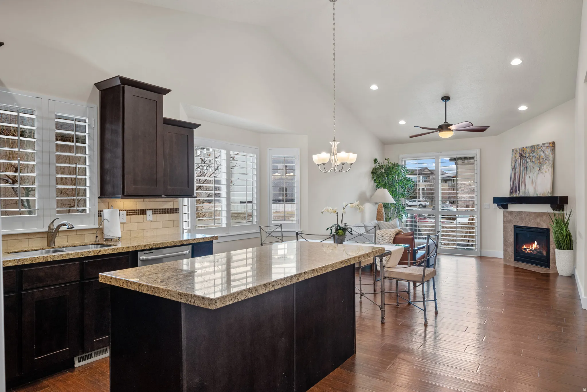 Kitchen featuring dark wood finish cabinetry, a center island, open floor plan, decorative backsplash, and lofted ceiling