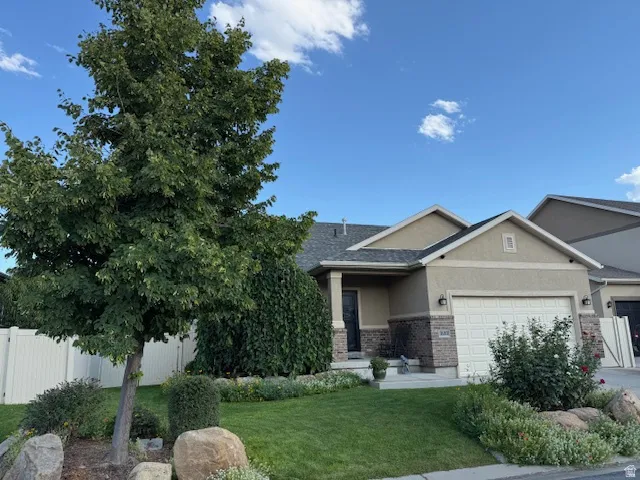 View of front of house with stucco siding, a garage, brick siding, a porch, and driveway