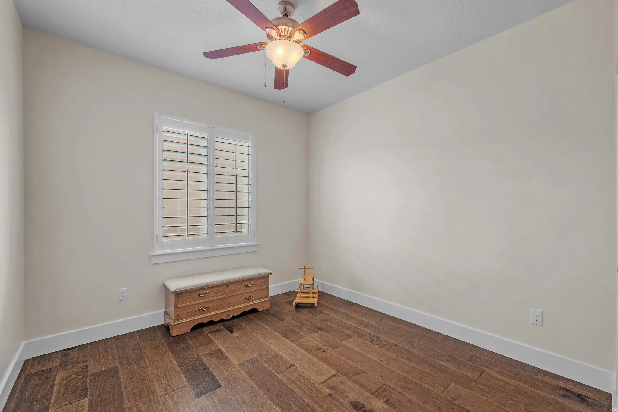 Empty room featuring dark wood-style floors and ceiling fan