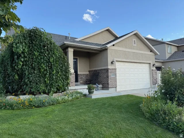 View of front facade with stucco siding, a front yard, a garage, and concrete driveway