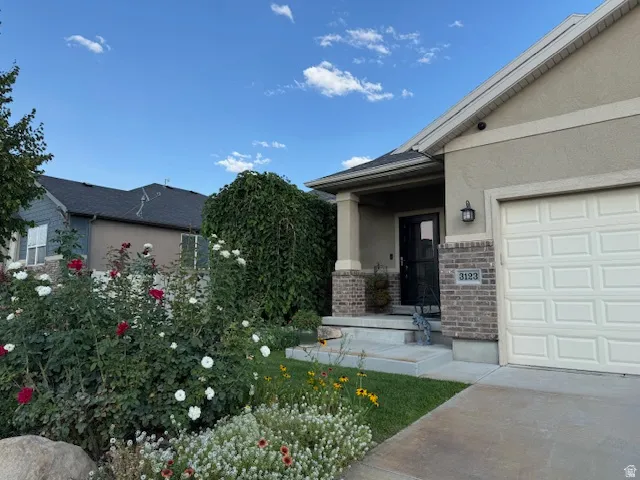 Entrance to property with stucco siding, a porch, brick siding, stone siding, and an attached garage