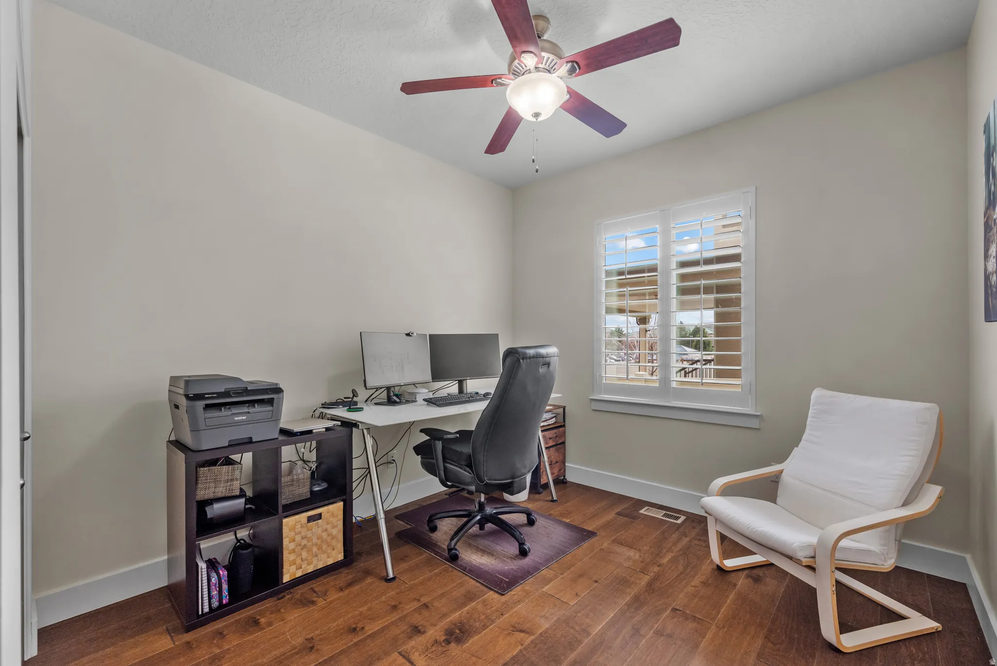 Office area featuring dark wood-type flooring and ceiling fan