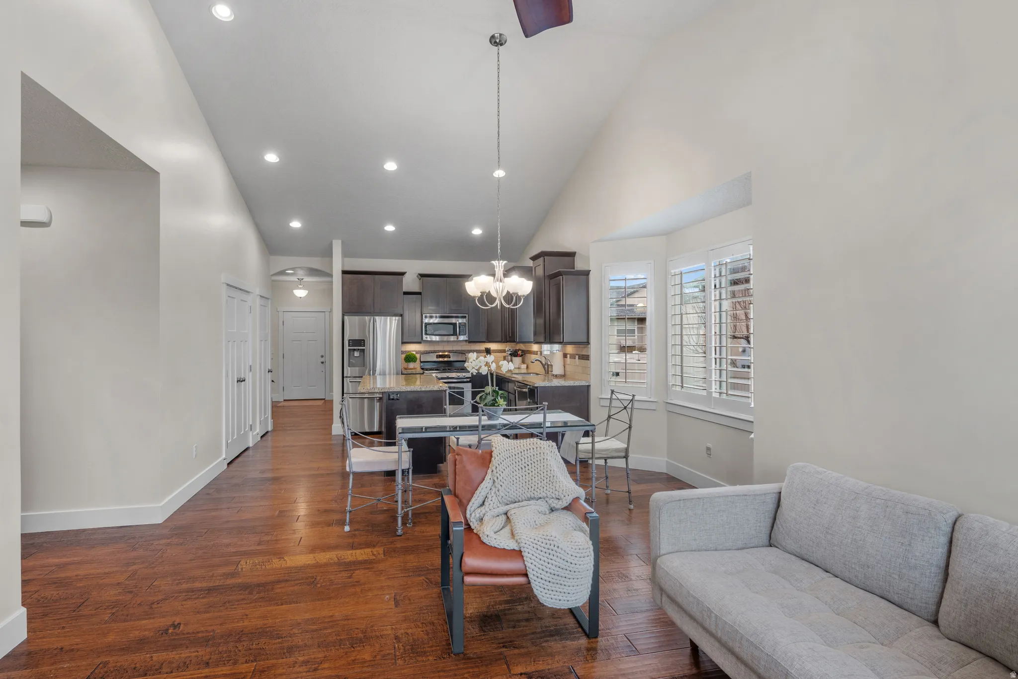 Living room featuring dark wood finished floors, lofted ceiling, and suspended lighting