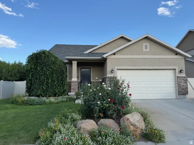 View of front of home featuring stucco siding, a garage, driveway, and covered porch