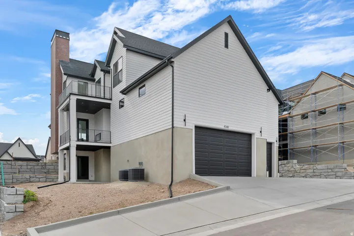 Modern farmhouse exterior featuring white siding, a dark gray garage door, and a multi-level balcony with black railings