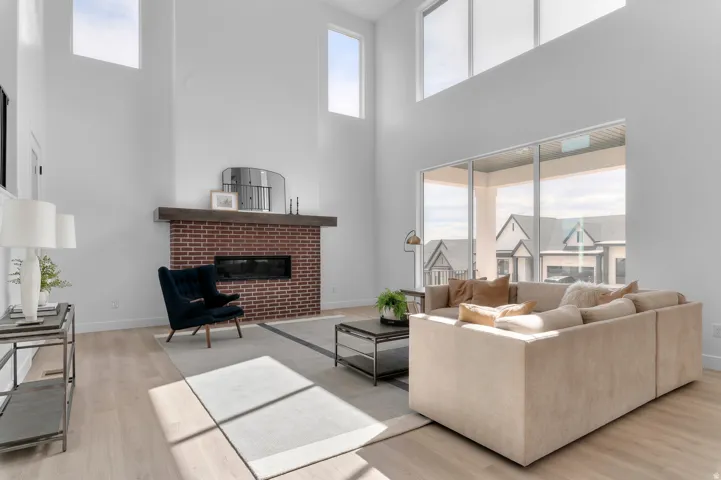 Open-concept living area with a brick fireplace, a dark wood mantel, and a linear electric firebox