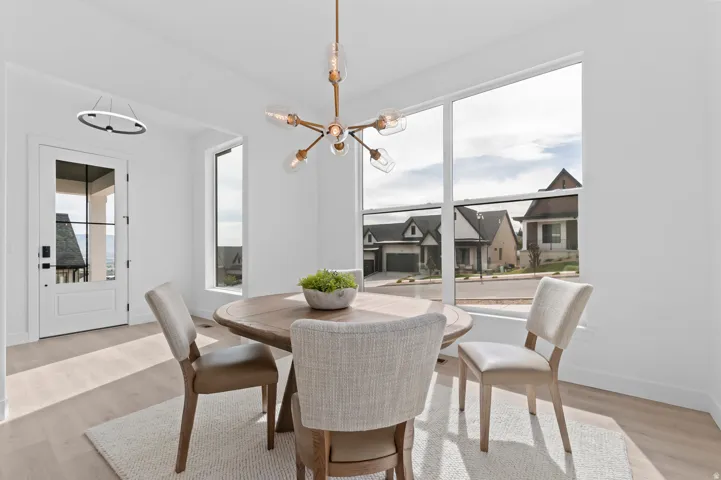 Bright interior space featuring a large picture window, a modern linear chandelier, and light wood-finish flooring