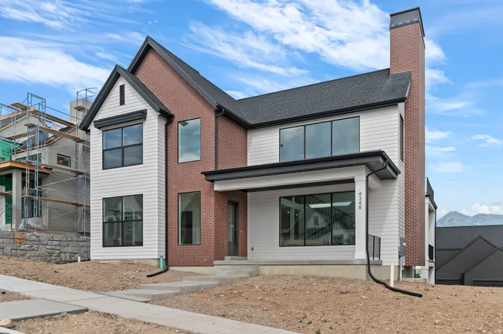 Contemporary exterior featuring mixed material siding, a prominent brick chimney, and dark-framed windows