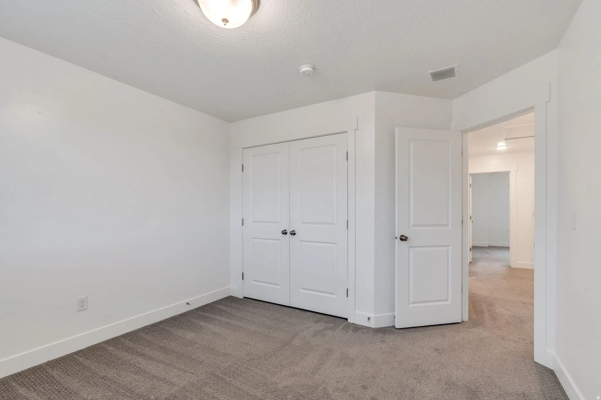 Unfurnished bedroom with light carpet, a closet, and a textured ceiling