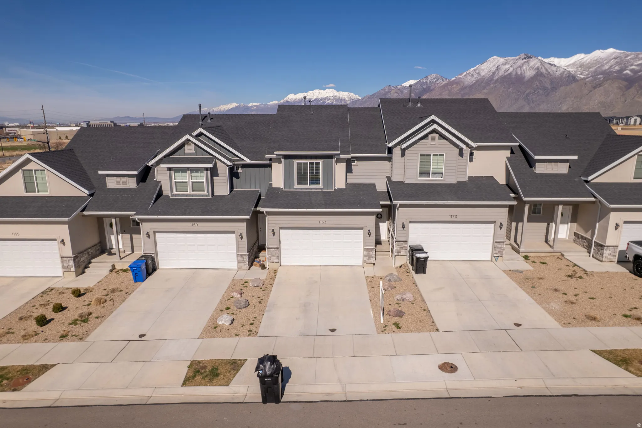 View of front of home with stone siding, a residential view, driveway, and a garage