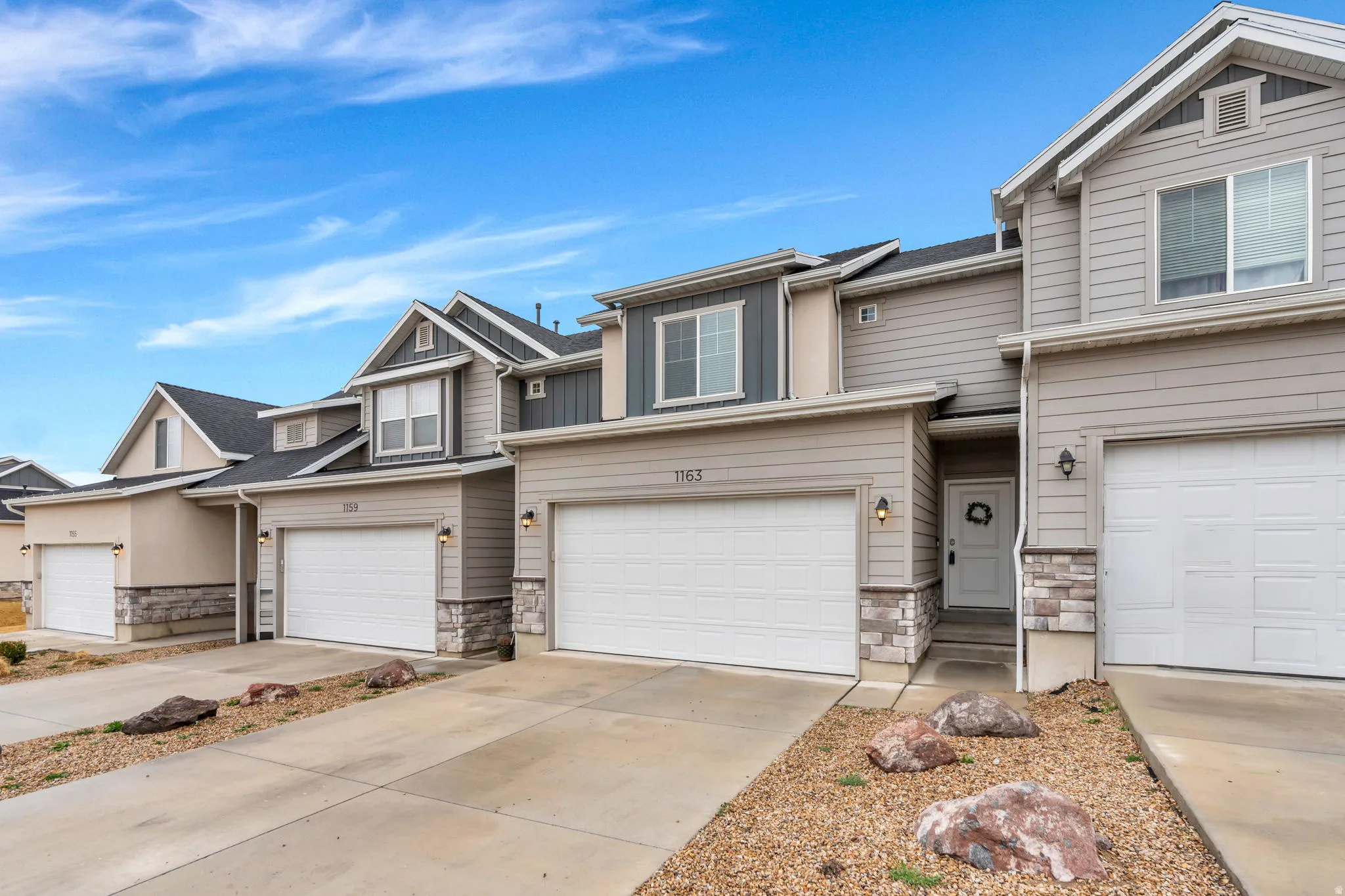 Craftsman inspired home featuring stone siding, a garage, and concrete driveway