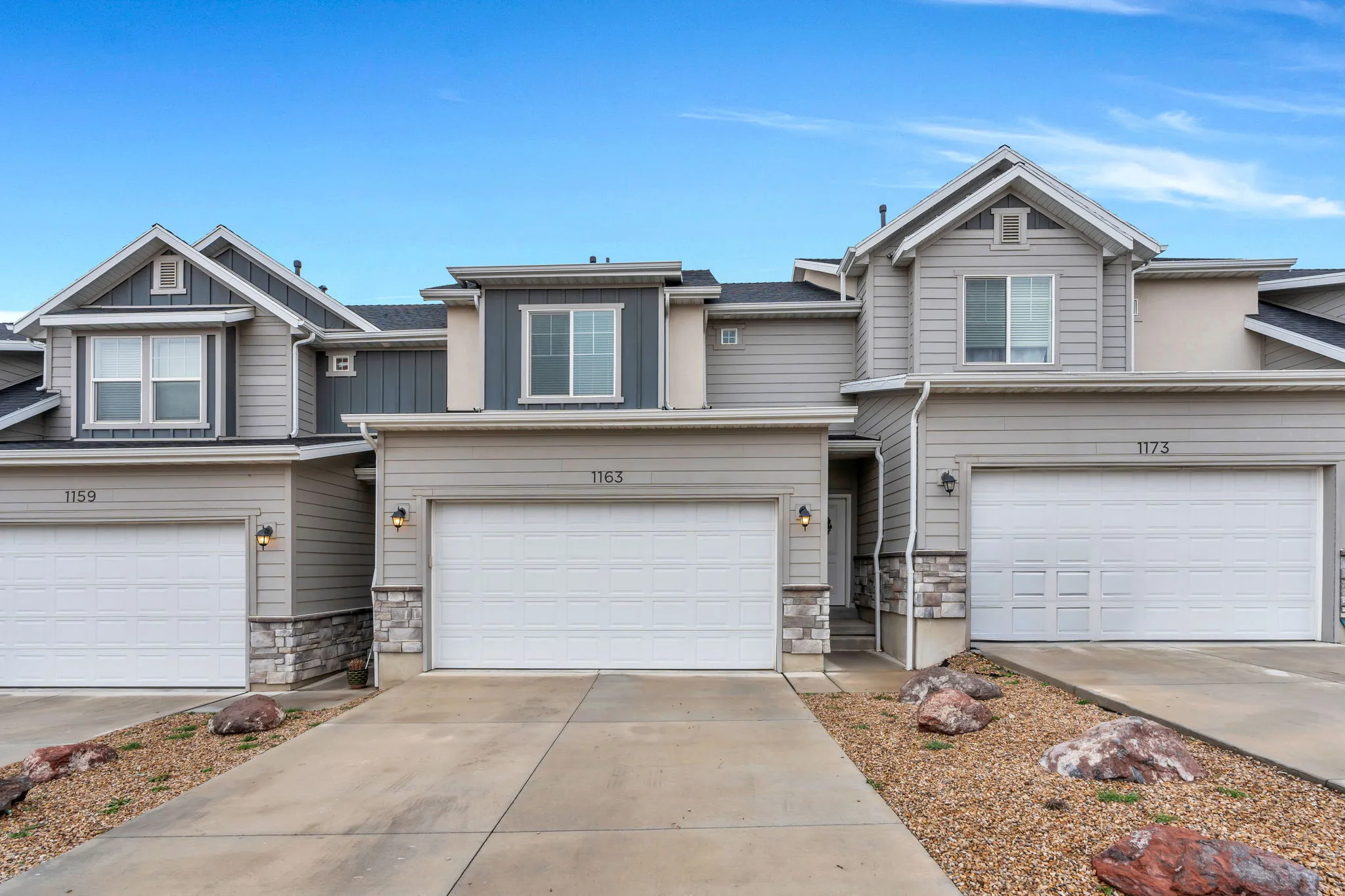 Craftsman inspired home featuring stone siding, a garage, concrete driveway, and board and batten siding